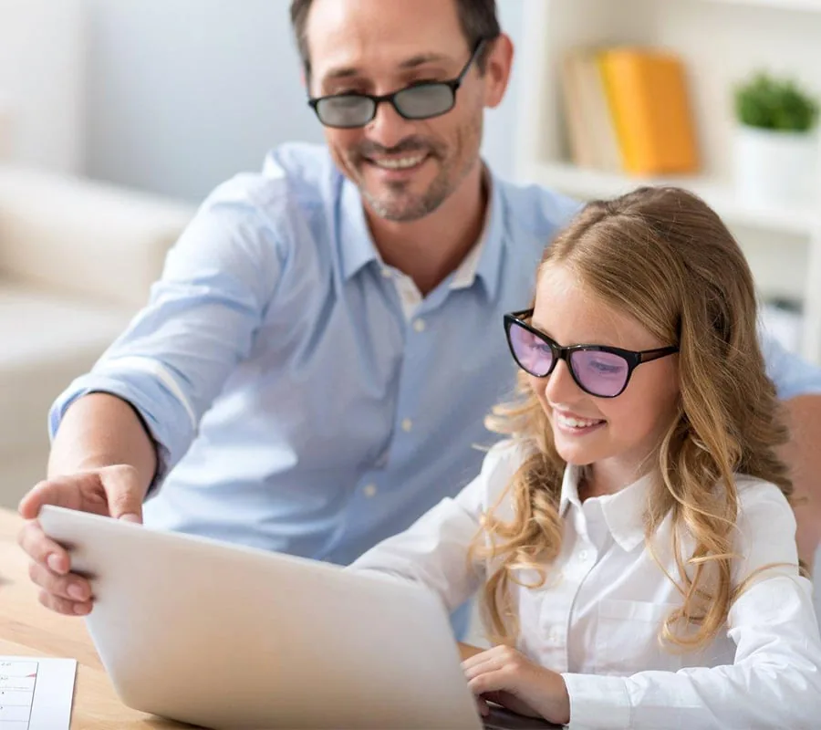 A father and his daughter reading together, the girl wearing tinted Irlen lenses
